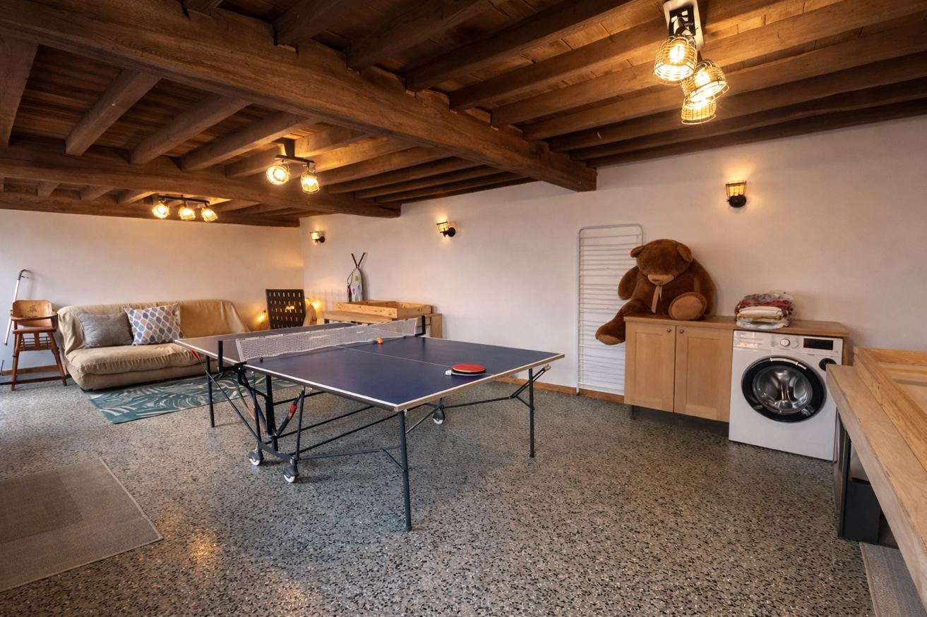 Salle de jeux 60m² avec poutres apparentes et ping-pong – Gîte Les Pétillières